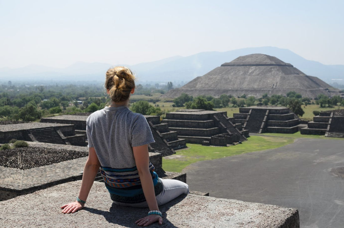 Young woman sitting on the top of pyramid overlooking Teotihuacan on a sunny day