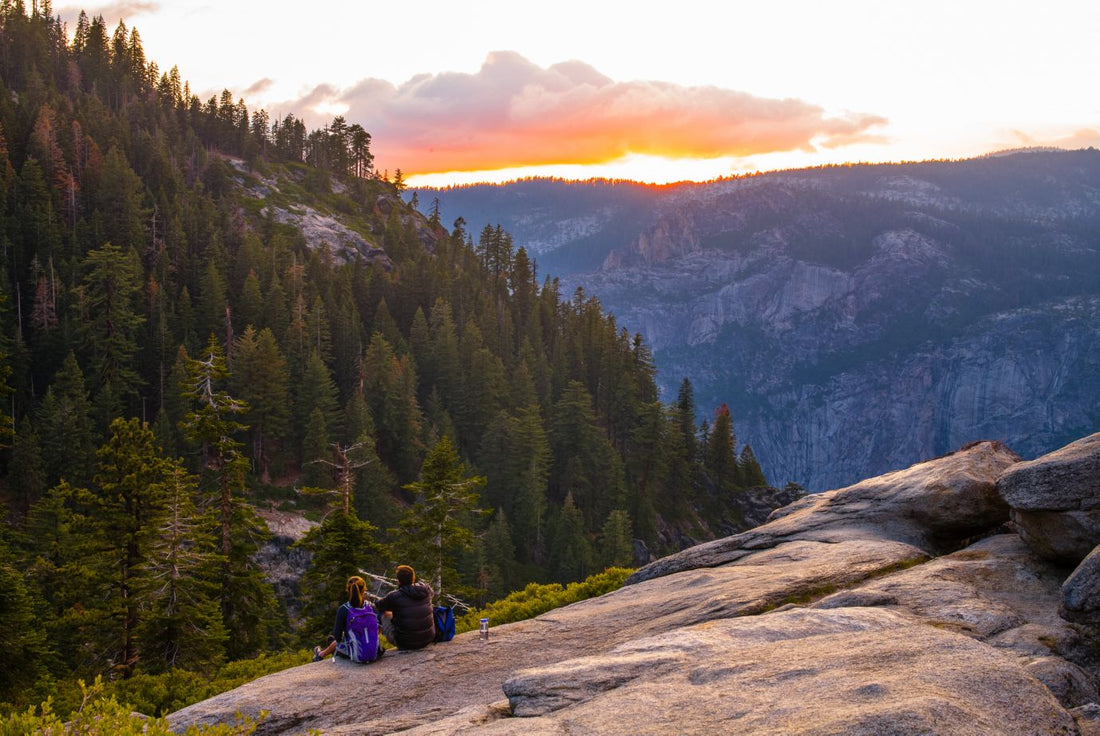 hikers watching a sunset on a cliff